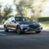 Front side view of 2022 Genesis G70 driving down road with blurred trees in background