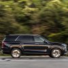 Side view of black 2022 Hyundai Palisade driving down road with trees in background