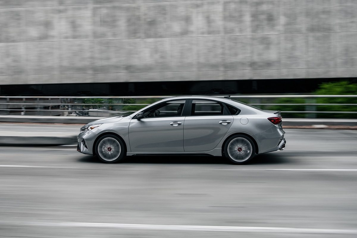 Exterior side view of a silver 2022 Kia Forte driving on a city street