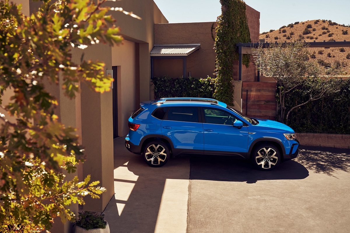 Side view of a blue 2022 Volkswagen Taos parked in front of a house in the desert