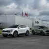 A white 2023 Kia Sportage SX and green 2023 Kia Sportage X-Pro are parked in front of Kia headquarters