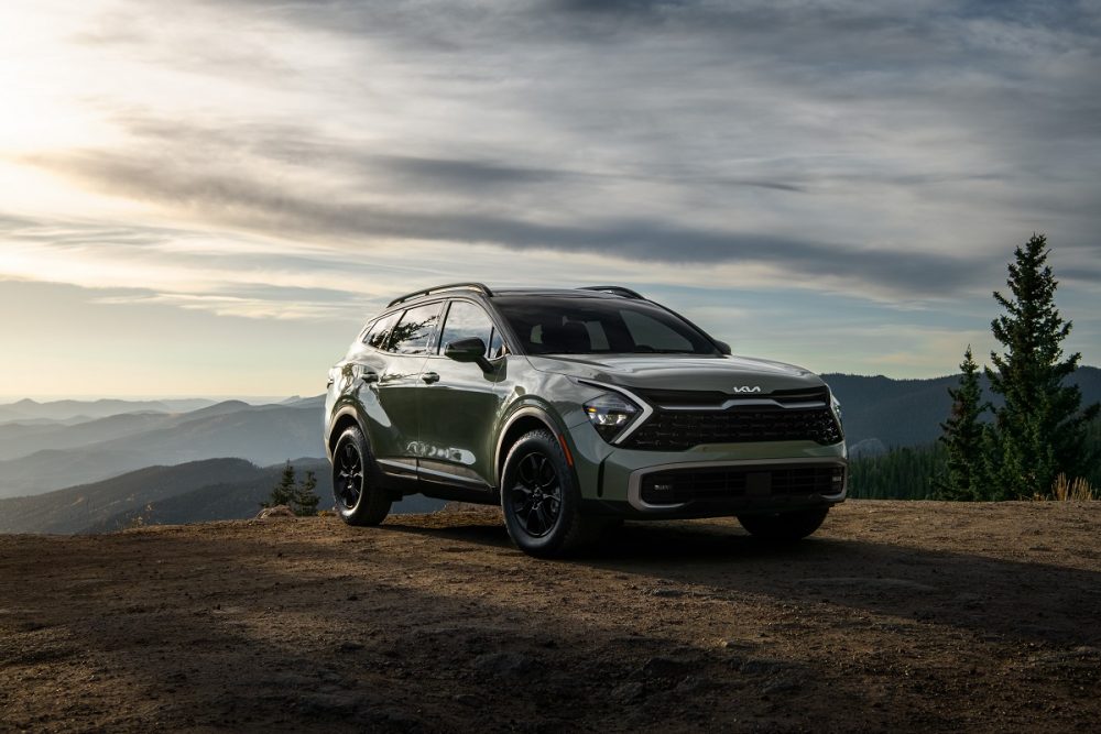 Front view of a green 2023 Kia Sportage X-Pro parked on a cliff at sunset