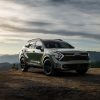 Front view of a green 2023 Kia Sportage X-Pro parked on a cliff at sunset