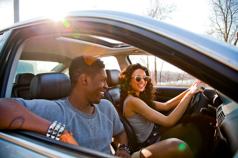 Female driver and male passenger smiling in a car