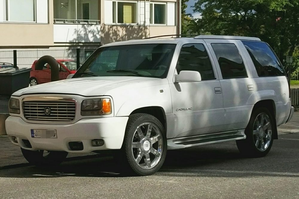 A white 1999 Cadillac Escalade parked on a city street