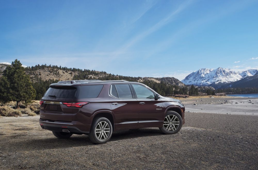 Rear side view of parked 2022 Chevrolet Traverse High Country with blue sky and mountains in background