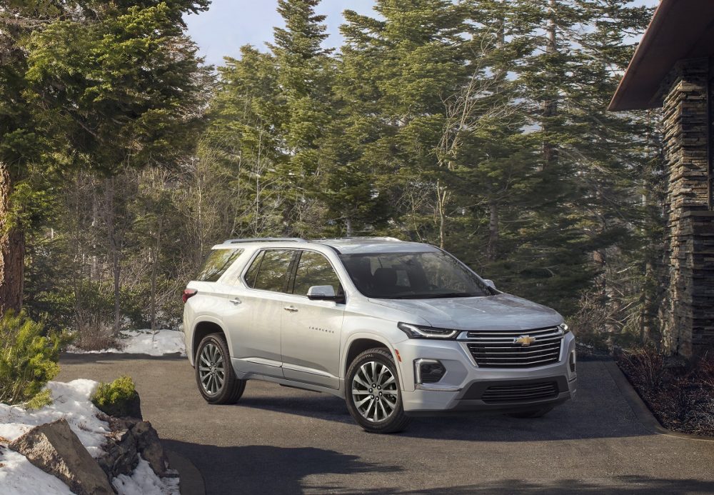 Front side view of white 2022 Chevrolet Traverse Premier parked with woods in background