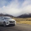 Front side view of 2022 Chevrolet Traverse Premier driving down road with clouds and mountains in background