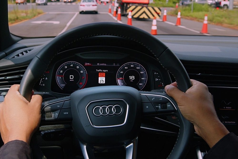 Close up of two hands on an Audi steering wheel with a highway work zone ahead