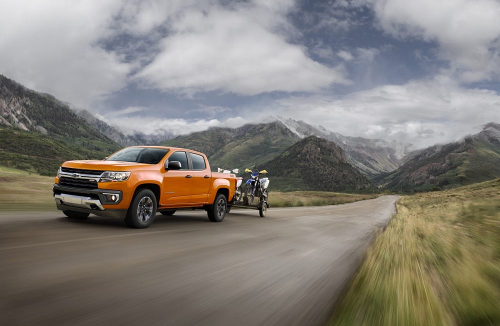 Front side view of 2021 Chevrolet Colorado towing trailer of motorbikes in the mountains