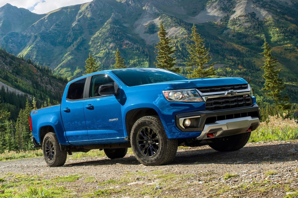 A bright blue 2022 Chevrolet Colorado Trail Boss sits among a mountainous area