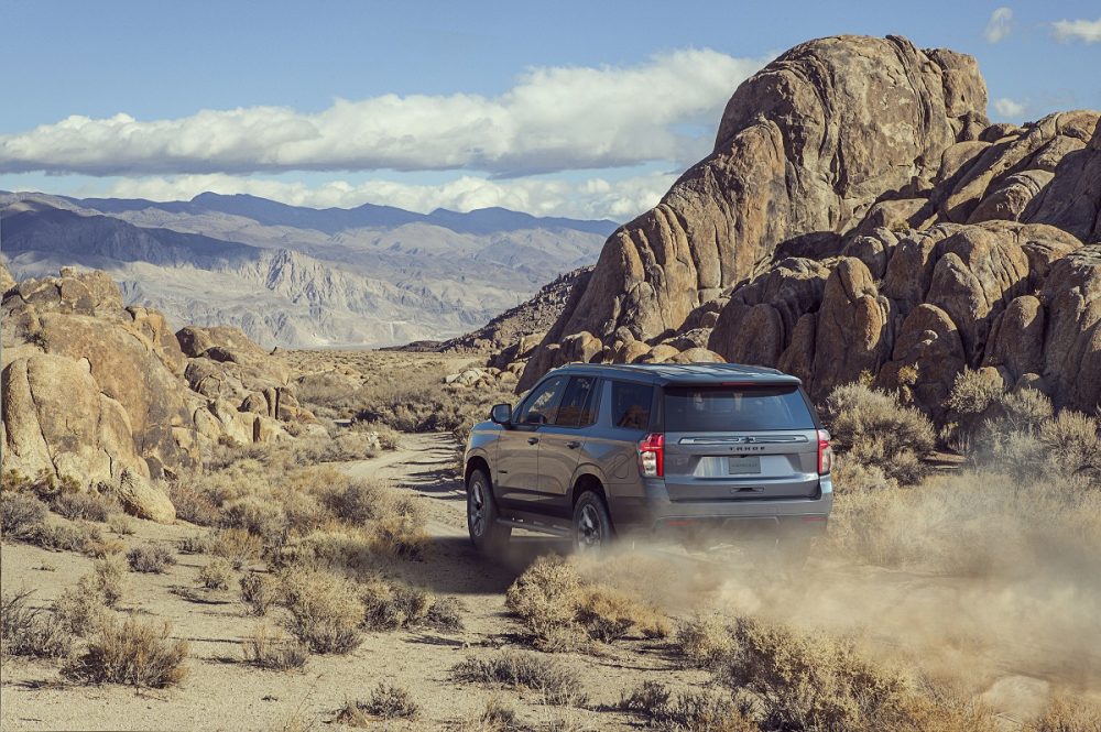 Rear side view of 2022 Chevrolet Tahoe Z71 kicking up dust cloud on mountain trail