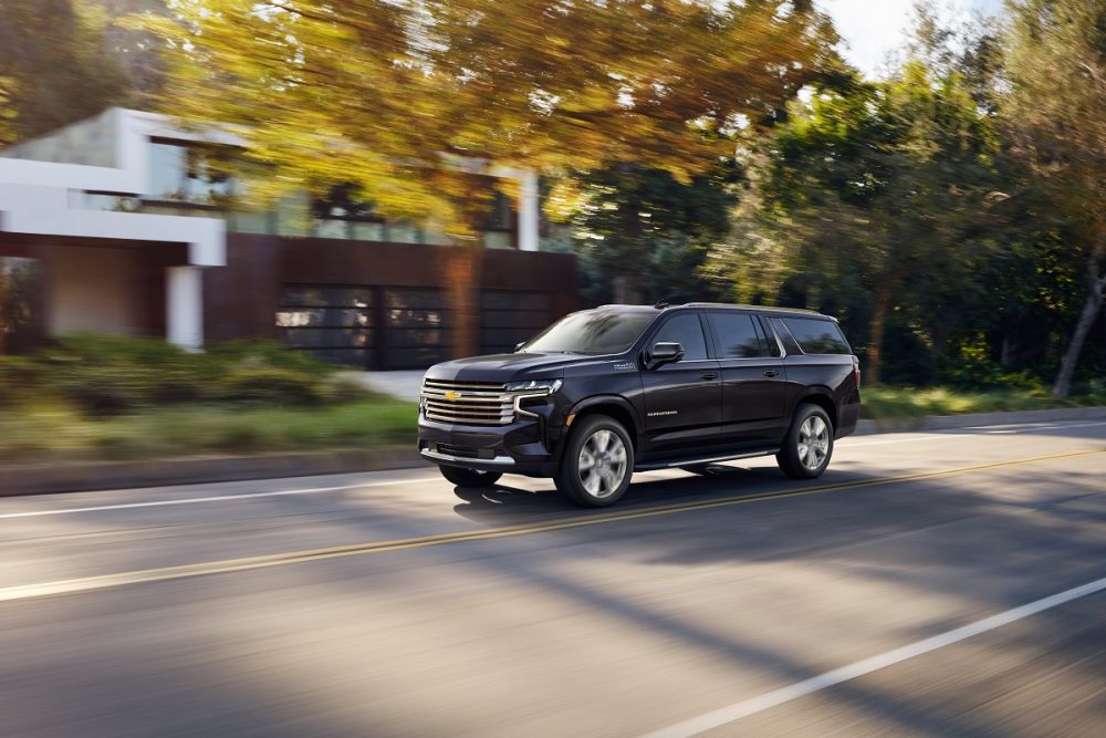 Front side view of black 2022 Chevrolet Suburban High Country driving down road