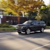 Front side view of black 2022 Chevrolet Suburban High Country driving down road