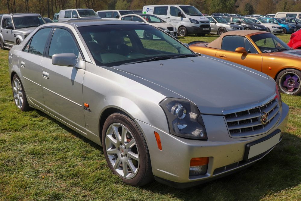 A silver 2006 Cadillac CTS parked on grass in a row of cars