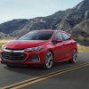 A red 2019 Chevrolet Cruze Hatchback drives on a highway road among the mountains