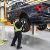 2022 Ford F-150 Lightning pre-production a UAW-represented worker inspects the tire of a truck at Rouge Electric Vehicle Center