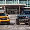 A 2022 Ford Maverick and Ford Bronco pose in front of Ford World Headquarters in Dearborn after winning the 2022 North American Truck of the Year and North American Utility of the Year awards