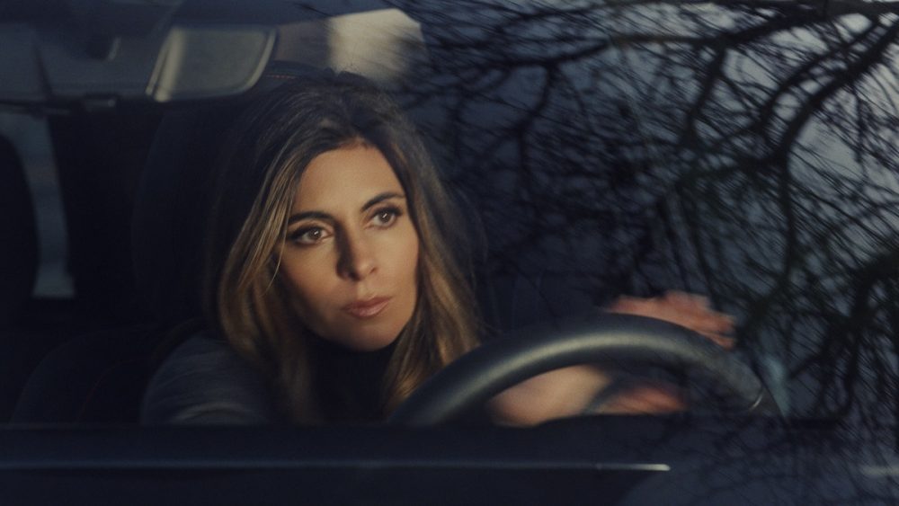 Portraying Meadow Soprano, actor Jamie-Lynn Sigler is seen through the windshield of a Chevrolet Silverado EV truck