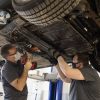 Two mechanics remove a lithium-ion battery from a car