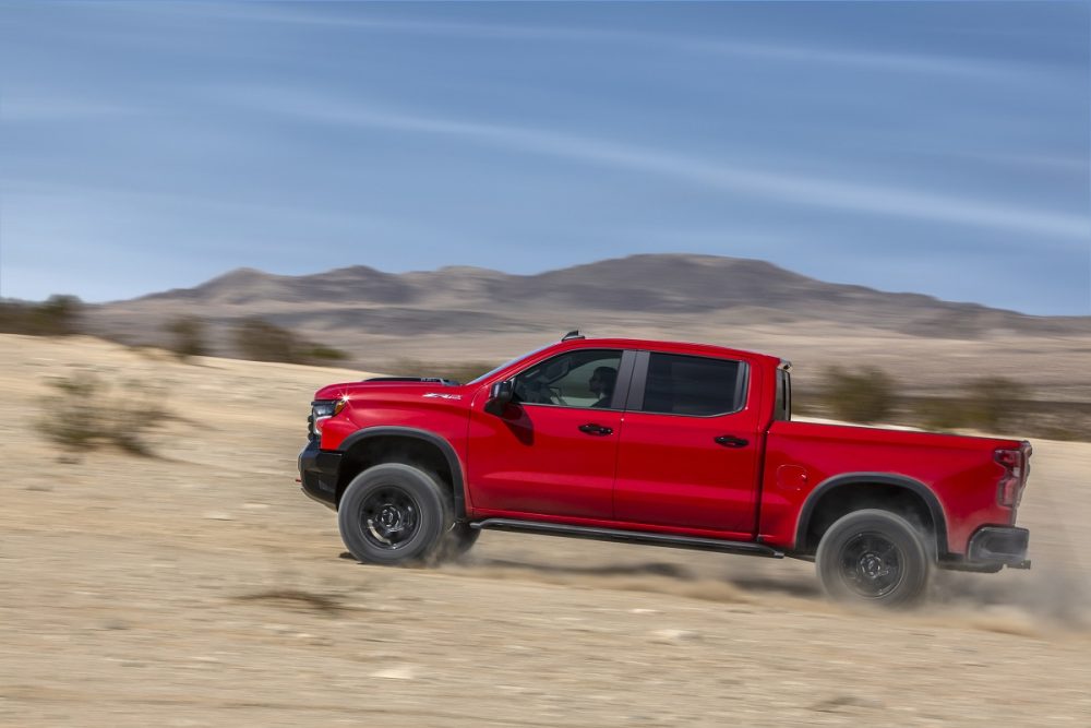 Side view of red 2022 Chevrolet Silverado ZR2 driving up desert hill