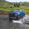 Front side view of blue 2022 Chevrolet Silverado ZR2 splashing across rocky stream