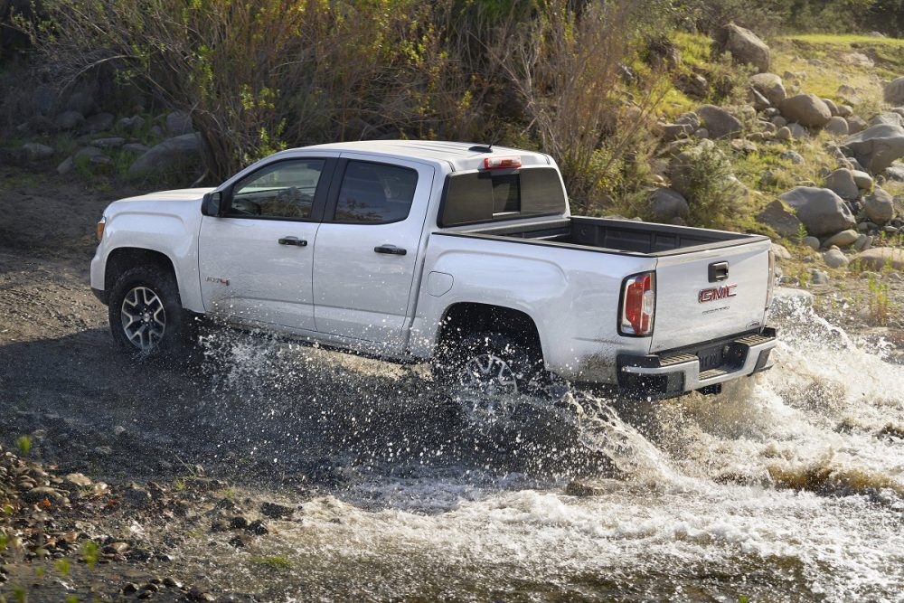 Rear side view of 2022 GMC Canyon AT4 driving through water