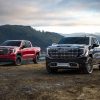 Front side views of red 2022 GMC Sierra AT4X and black GMC Sierra Denali Ultimate parked side by side with mountains in background