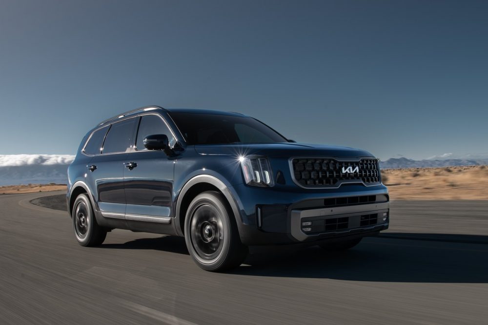 Exterior view of a blue 2023 Kia Telluride driving on a desert highway