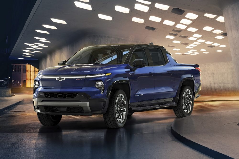 Blue 2024 Chevrolet Silverado EV parked at night in front of a building