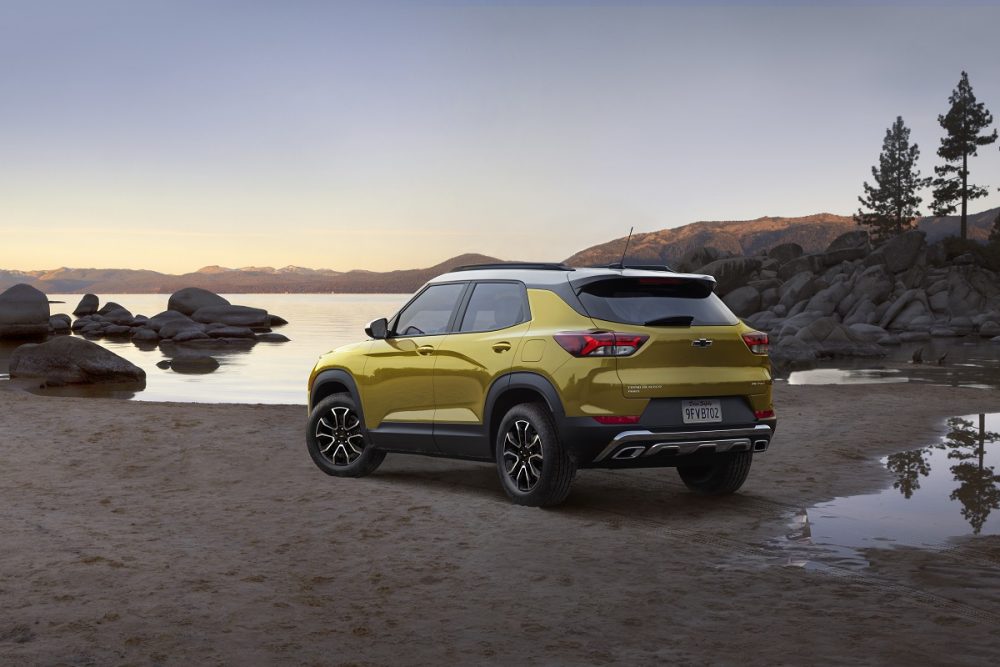 Rear side view of yellow 2023 Chevrolet Trailblazer ACTIV parked with lake in background