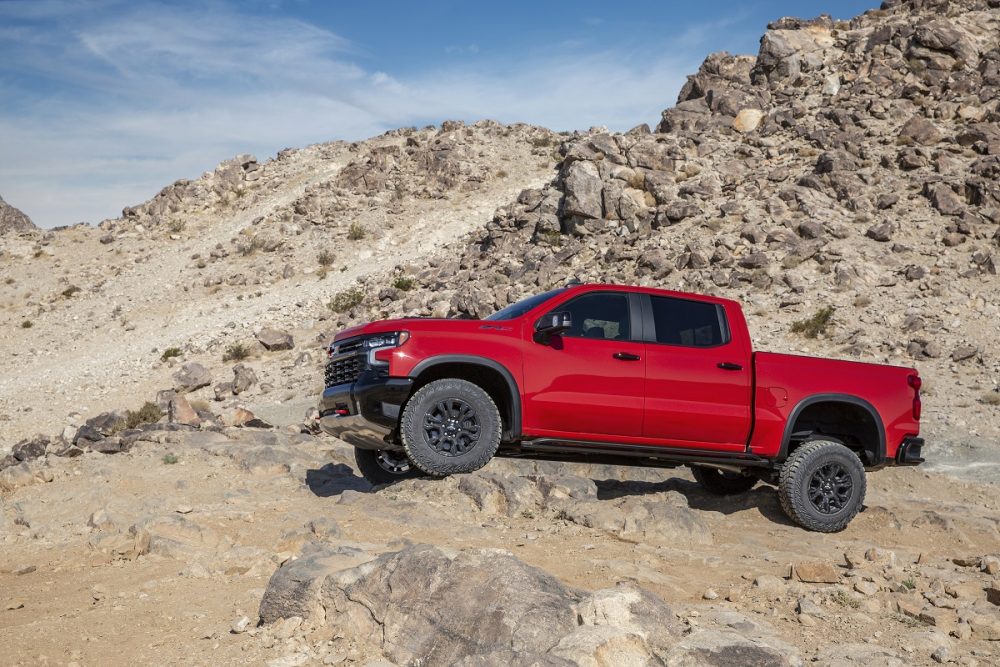 Side view of red 2022 Chevrolet Silverado ZR2 driving over rocks