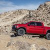 Side view of red 2022 Chevrolet Silverado ZR2 driving over rocks