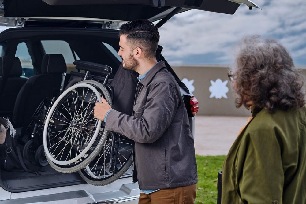 Man putting a wheelchair in the back of a vehicle