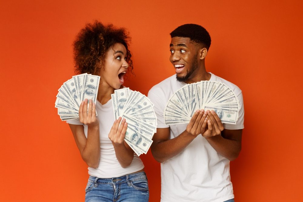 Two young people holding cash money