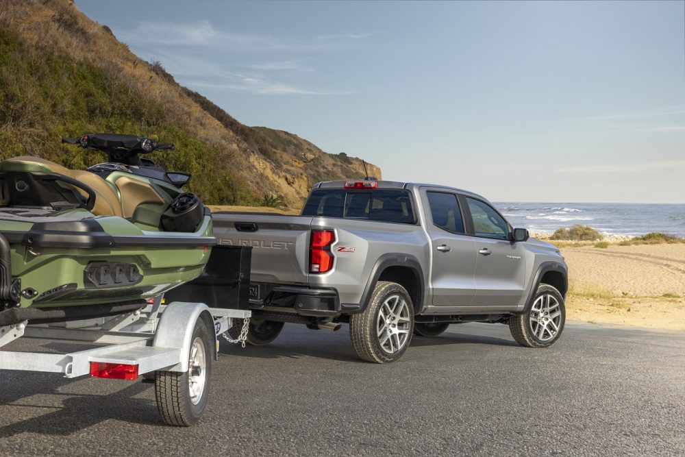 Rear side view of 2023 Chevrolet Colorado Z71 towing a boat and trailer near the water