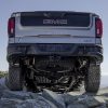 A view of the 2023 GMC Sierra 1500 AT4X AEV Edition's rear underside as it drives over rocky terrain