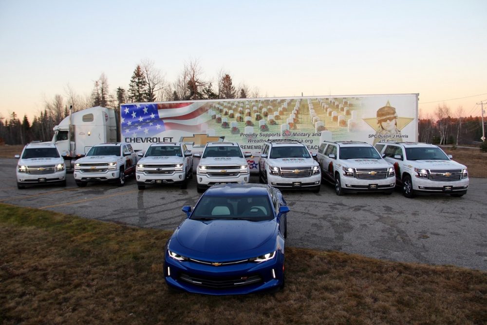 Decorated Chevy vehicles in front of a truck with an American flag on it