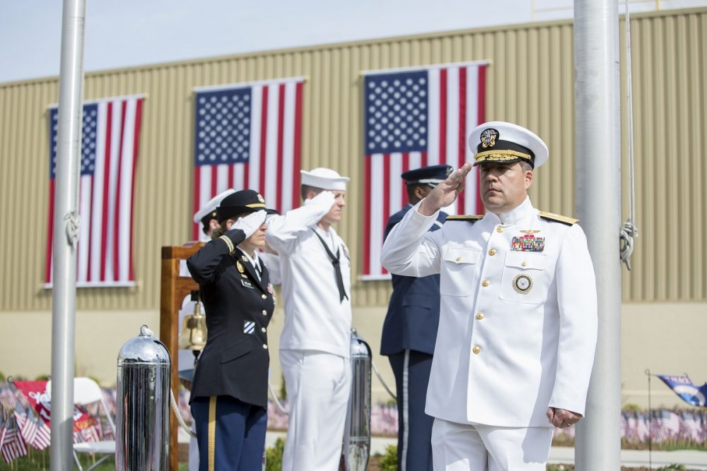 Military members saluting with American flags behind them