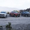 From left, the 2023 GMC Canyon AT4, Canyon AT4X, and Canyon Denali sit parked next to each other against a mountain backdrop