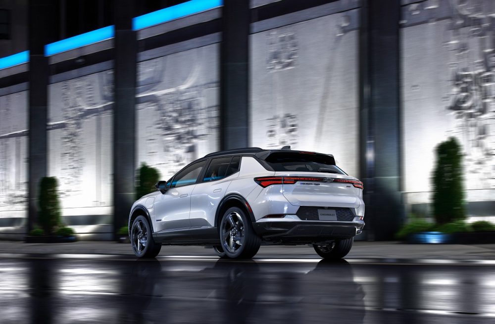 Rear side view of 2024 Chevrolet Equinox EV 3RS parked in front of building at night