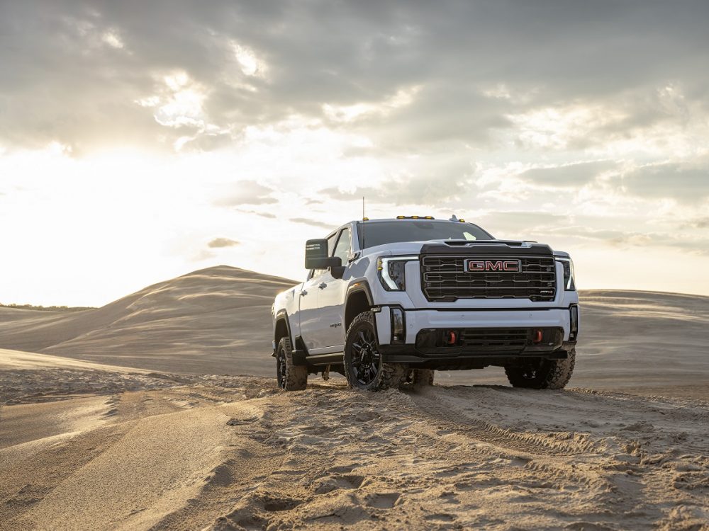 Front view of white 2024 GMC Sierra HD AT4 at top of sandy hill