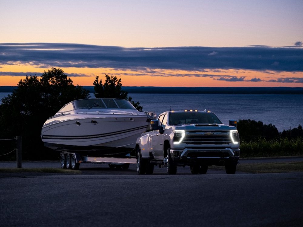 Front side view of 2024 Chevrolet Silverado 3500HD LTZ towing boat at sunset