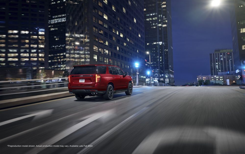 Rear side view of red 2023 Chevrolet Tahoe RST Performance Edition driving through city at night