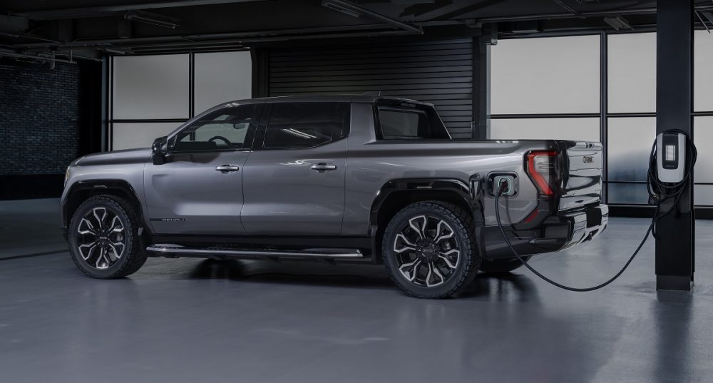 Side view of 2024 GMC Sierra EV Denali Edition 1 hooked up to charger