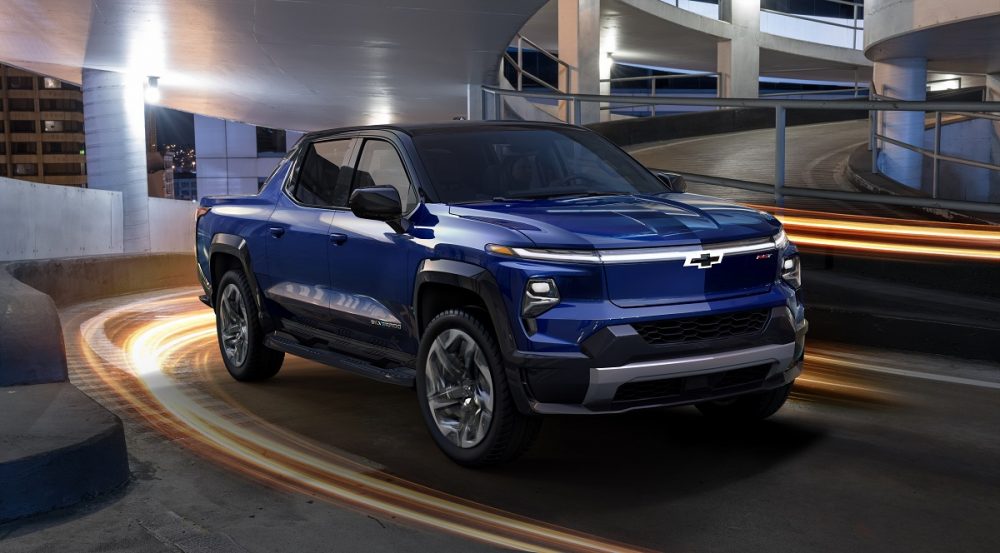 Front side view of blue 2024 Chevrolet Silverado EV RST rounding corner at night