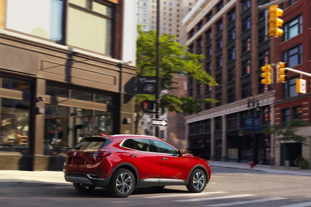 Rear side view of red 2023 Buick Envision driving on city street