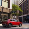 Rear side view of red 2023 Buick Envision driving on city street