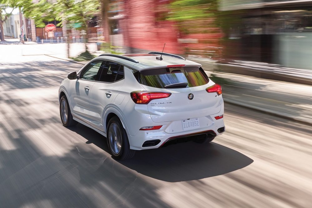 Rear side overhead view of white 2023 Buick Encore GX driving on street