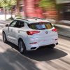 Rear side overhead view of white 2023 Buick Encore GX driving on street